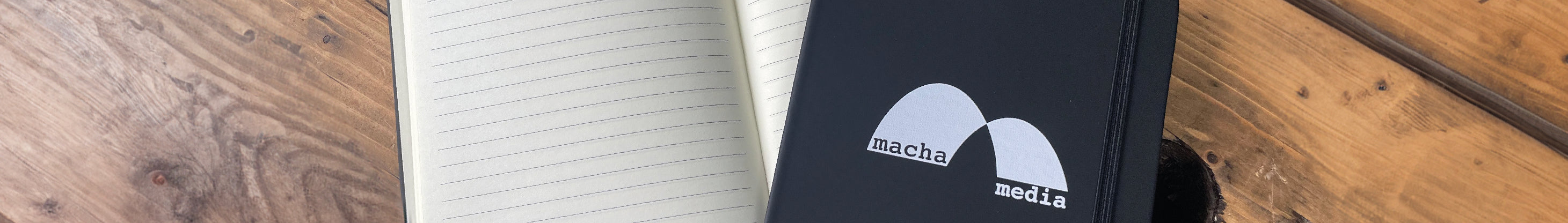 black Notebook with logo uv printed on the front, showing the inside of a lined notebook