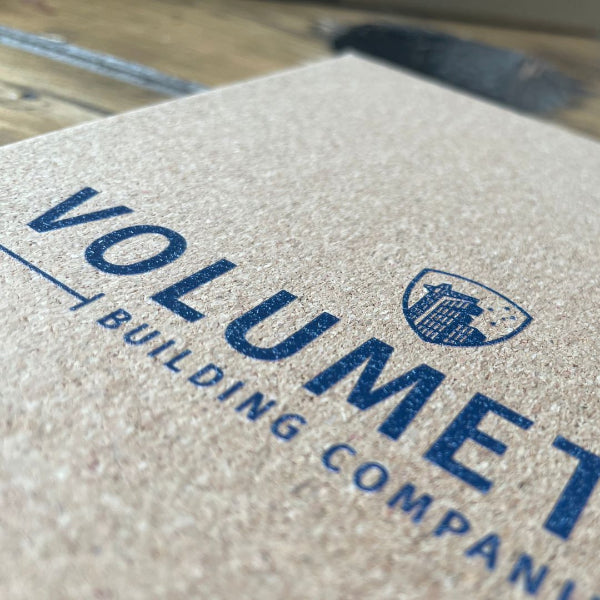 Close up of a Cork Notebook with a UV printed logo, with a black elastic band and a pen holder.