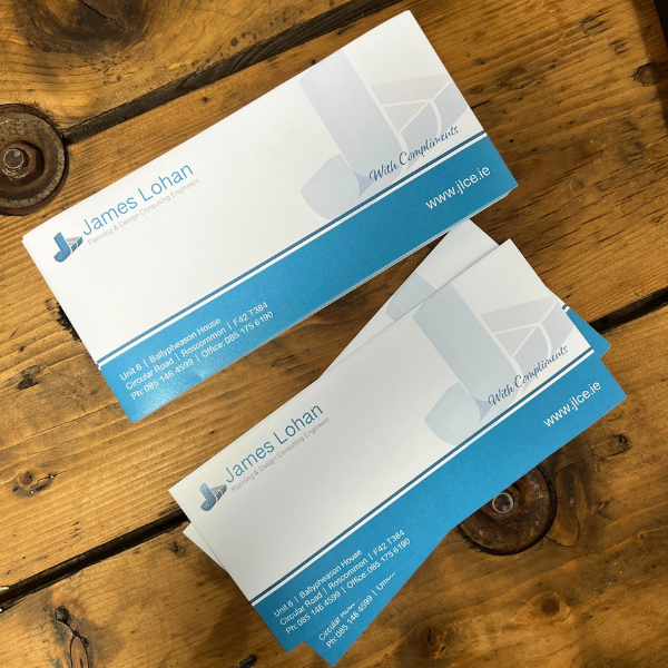 Blue and white compliment slips on wooden table