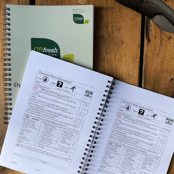 Green and white Gilfresh wire bound booklet on wooden table