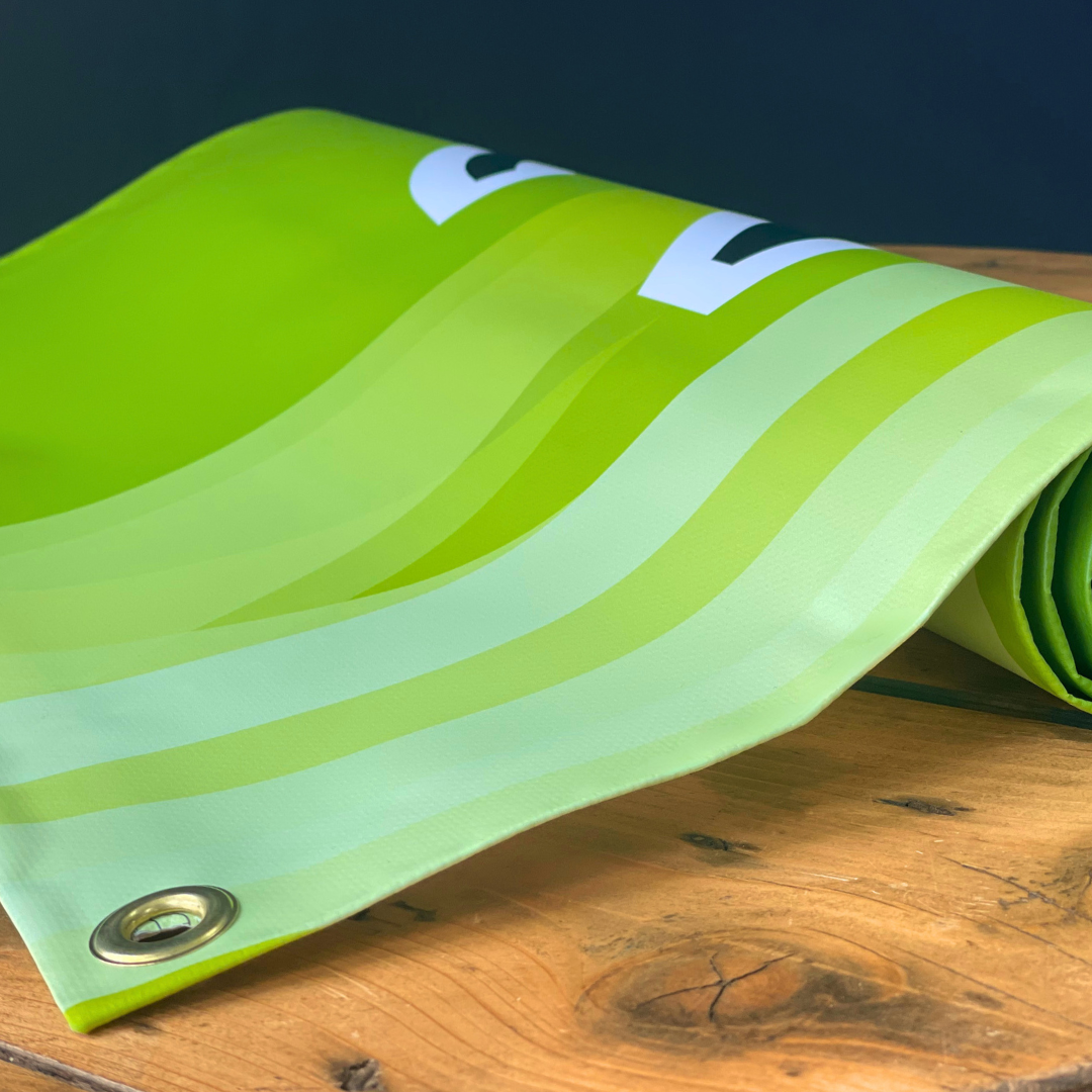 Green fabric with wavy pattern and grommet on wooden surface