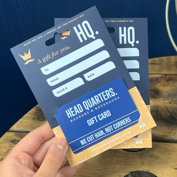 Head Quarters Barbers & beverages gift card holder held over wooden table