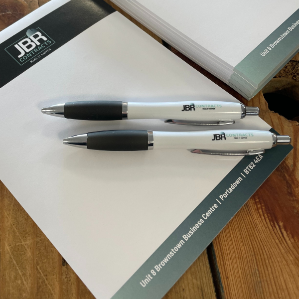 Two pens with JBR branding on a A6 Notepad with JBR text.