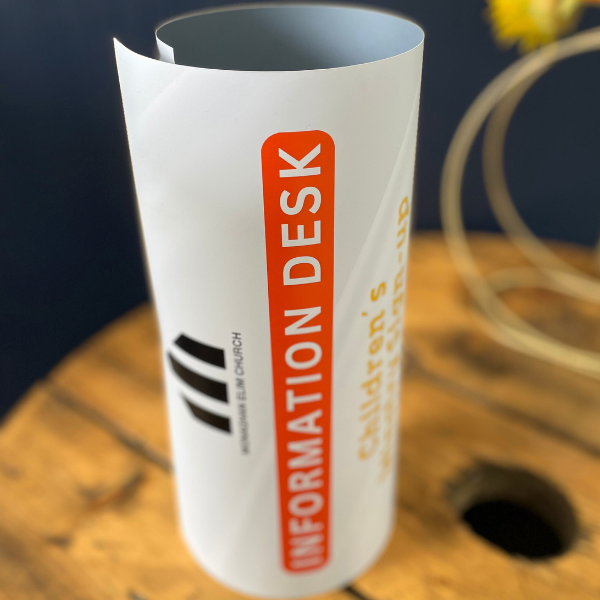 White and orange poster rolled up on wooden table