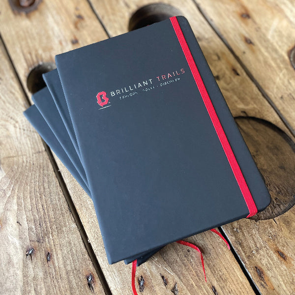 Black Notebook with a red ribbon, printed with a UV printed logo for Brilliant Trails.