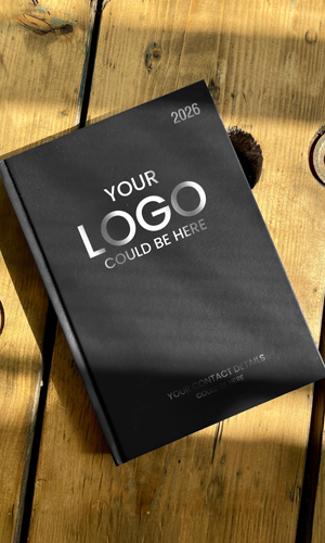 Black 2026 diary with 'Your Logo Could Be Here' text on a wooden surface