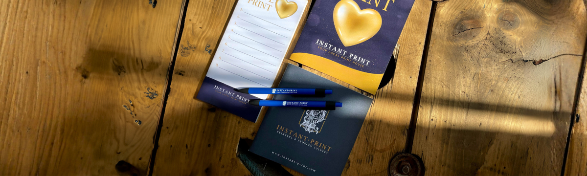 Instant Print Notepad, Pen and Booklet on Wooden Table