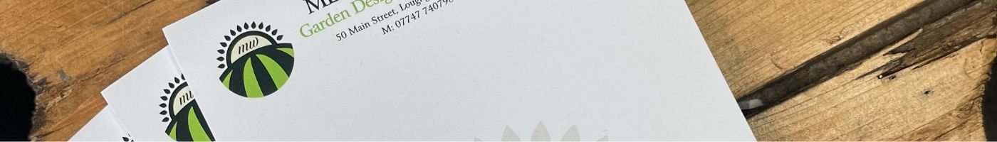 Notepads for a gardening company displayed on a wooden table.