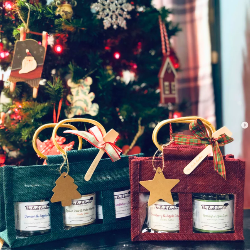 Two gift boxes with candles in front of a decorated Christmas tree