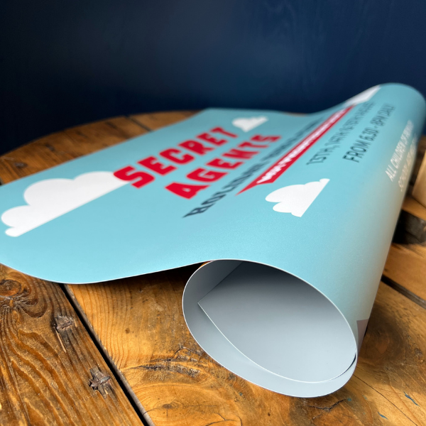 Rolled-up poster with 'Secret Agents' text on a wooden surface