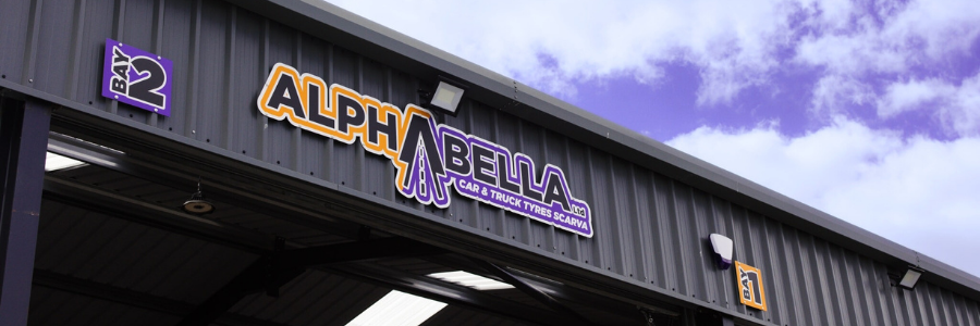 Alphabella logo on a building with a blue sky background