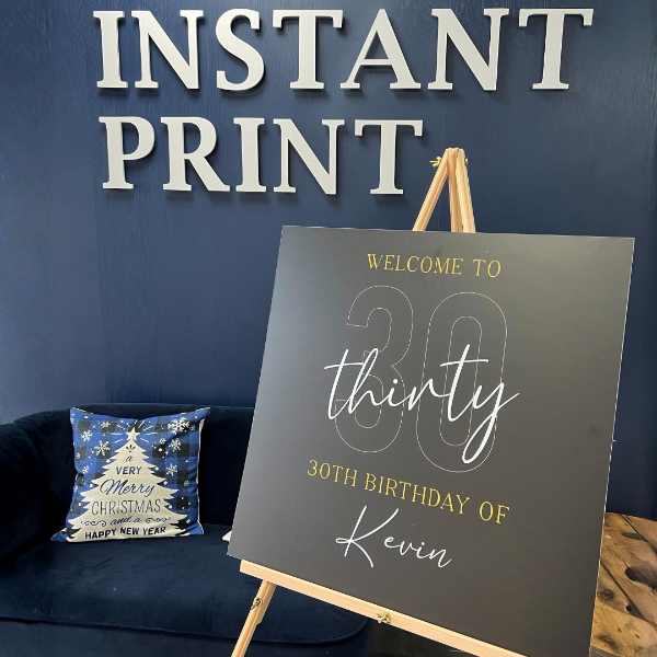 Decorative sign for a 30th birthday celebration on an easel against a blue wall with 'Instant Print' text.