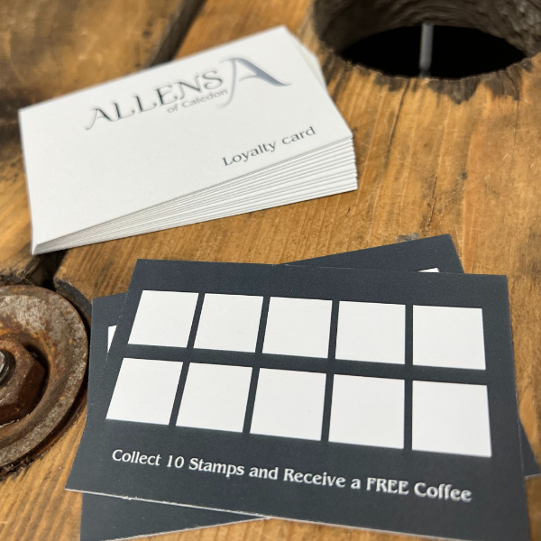Stack of loyalty cards with a free coffee offer on a wooden surface, featuring Allen's Coffee branding.