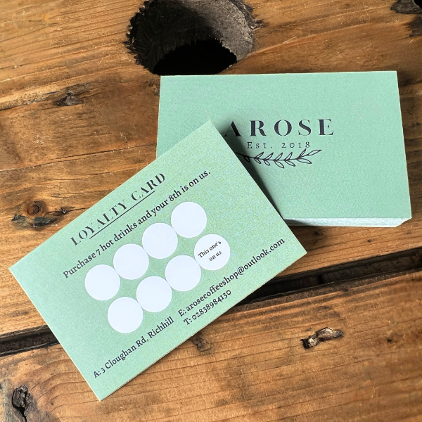 Two loyalty cards on a wooden surface, one with a coffee shop logo and text, the other plain.