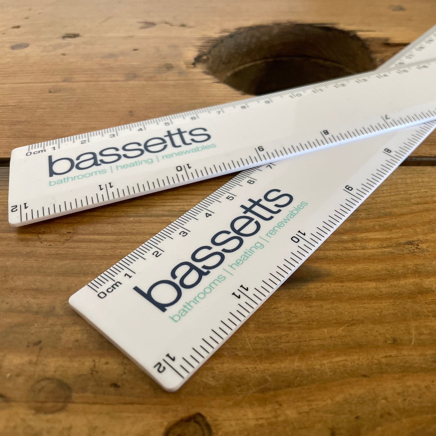 Branded rulers for Bassets displayed on a wooden table.