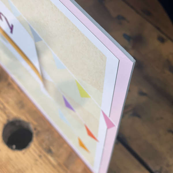 A close-up of a white PVC Foamex Board with a matt vinyl print displaying colorful geometric shapes.