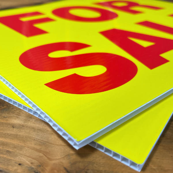 Yellow and red 'For Sale' correx sign on wooden table