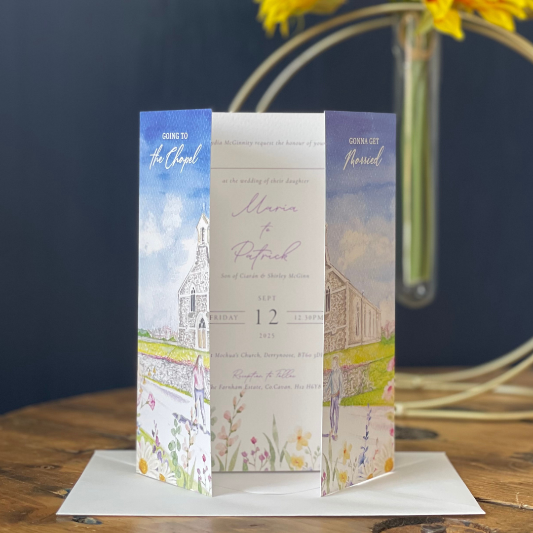 Wedding invitation with church illustration on a wooden table with flowers in the background