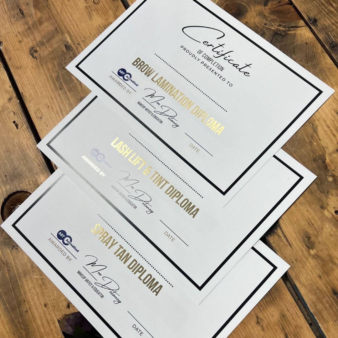 Gold foil certificate for beauty school, displayed on a wooden table.