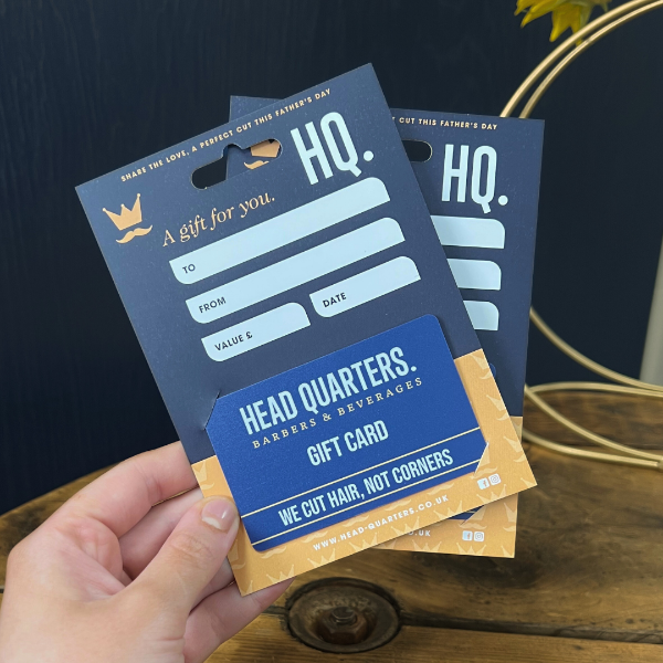 HQ Barbers gift holder against blue background and wooden table