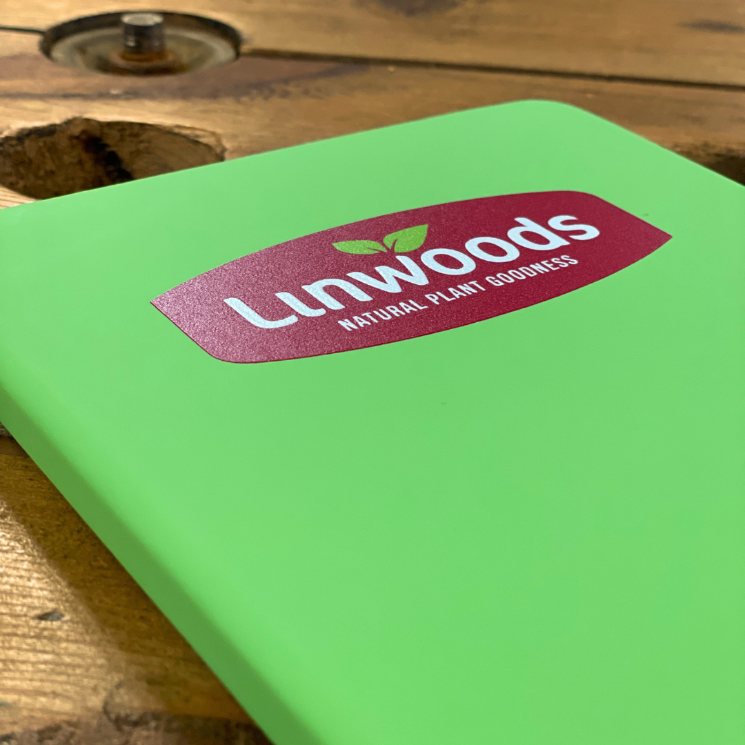 Green A5 Notebook with Linwoods logo on a wooden surface