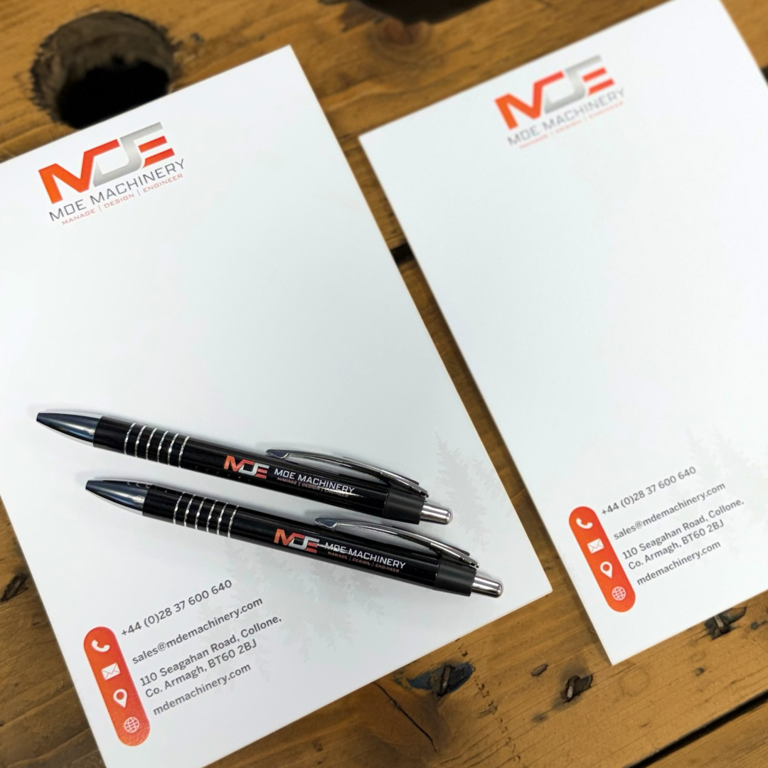 MDE Machinery note pads and pens on wooden table