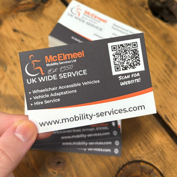 Grey and orange business cards held over wooden table