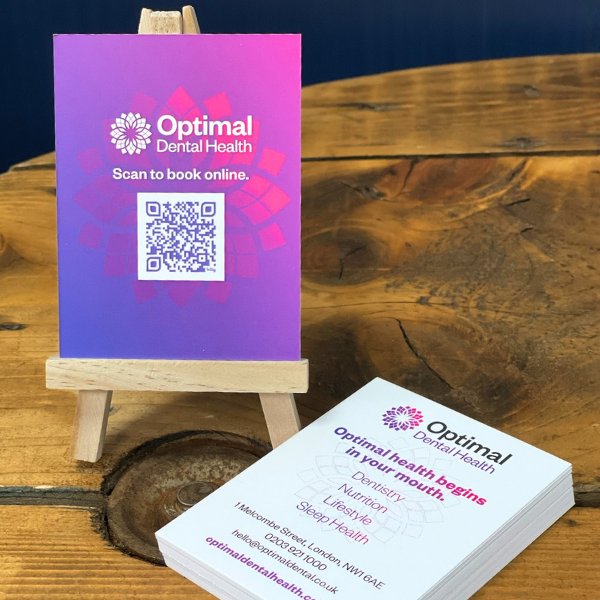 Pink and purple rectangle business cards on a mini easle on wodden table with blue background
