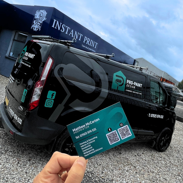 Black van with 'Pro-Paint Design' branding, held in front of a building with 'Instant Print' branding.