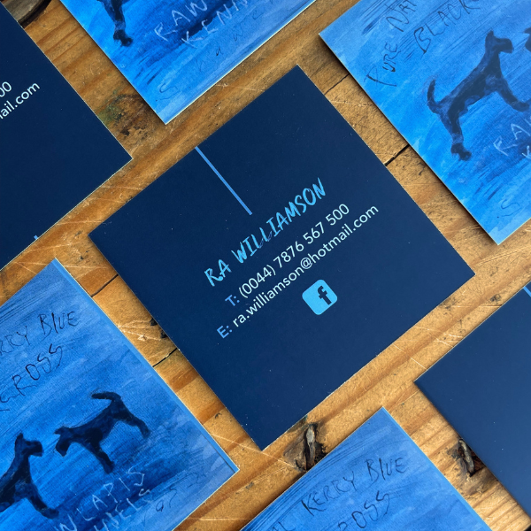 Blue square business cards with contact information on a wooden surface