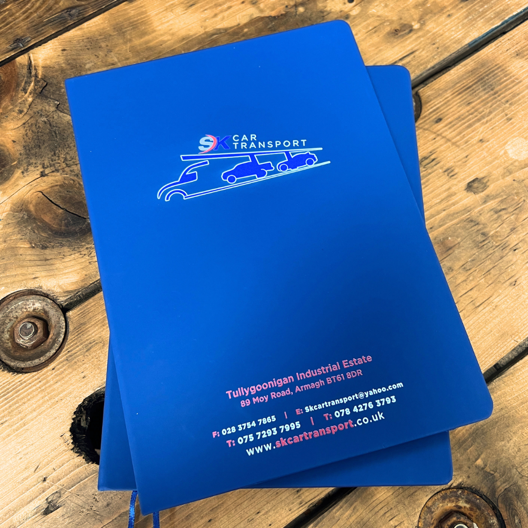 Blue A4 Notebook with SK Car Transport stacked on wooden table