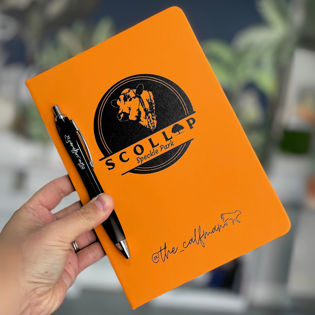 Orange notebook with 'Scollap Speckle Park' branding held by a hand with a pen.