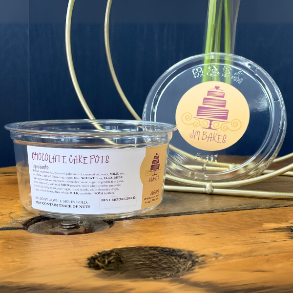 Clear container with 'Chocolate Cake Pots' label on a wooden surface with a blue background