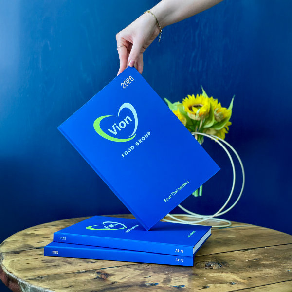 Blue2026 Diary with Vion Food Group logo on a wooden table against a blue background