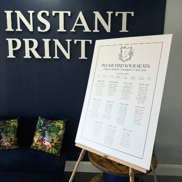 Easel with a seating chart against a dark wall with 'Instant Print' text.