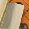 Orange notebook flicking through the pages stacked on top of other orange notebooks