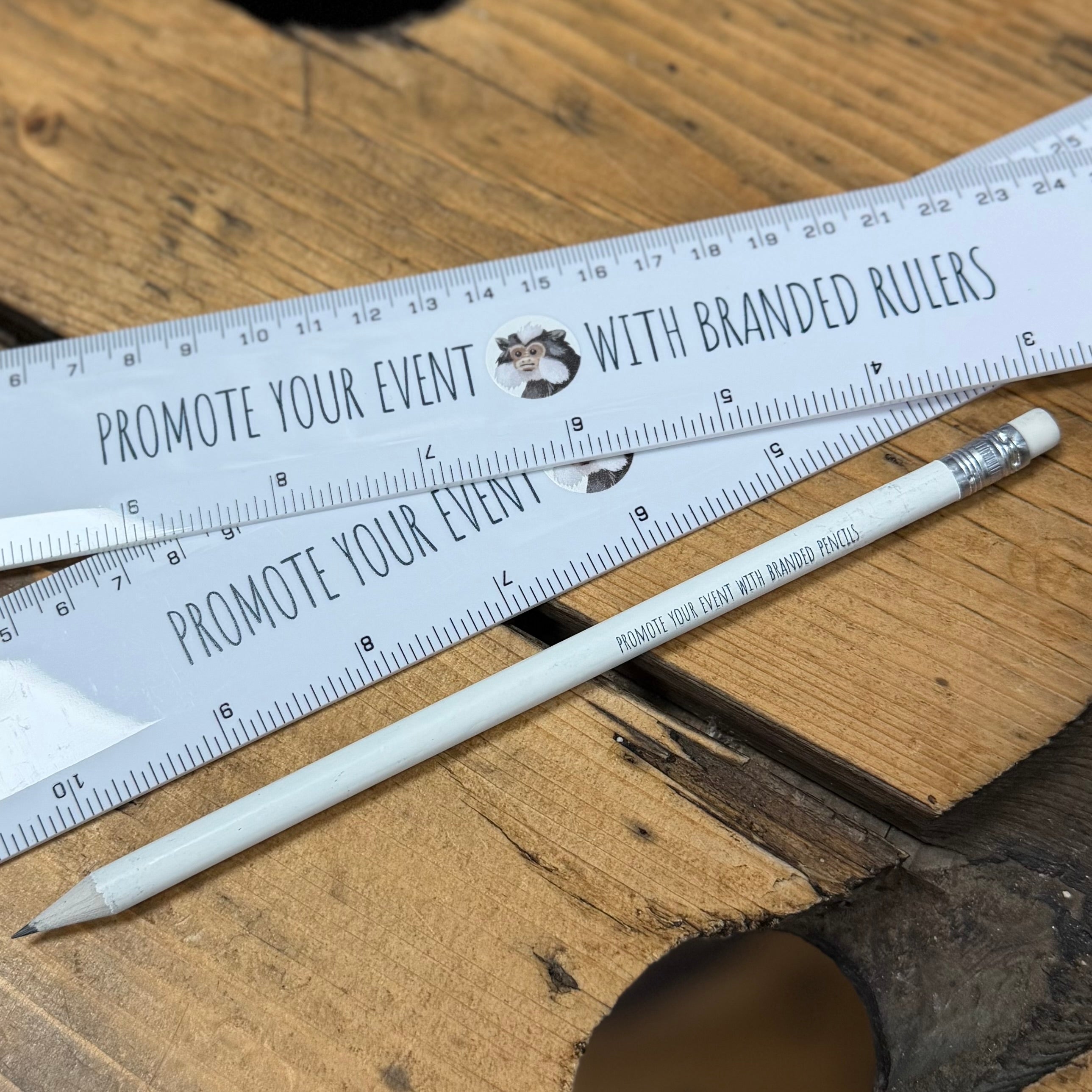 UV printed branded pencils and rulers, on a wooden table.