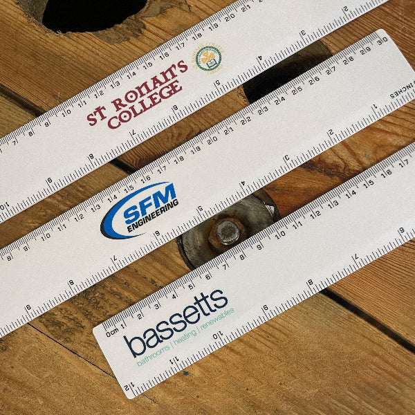 3 Rulers laid out on wooden table