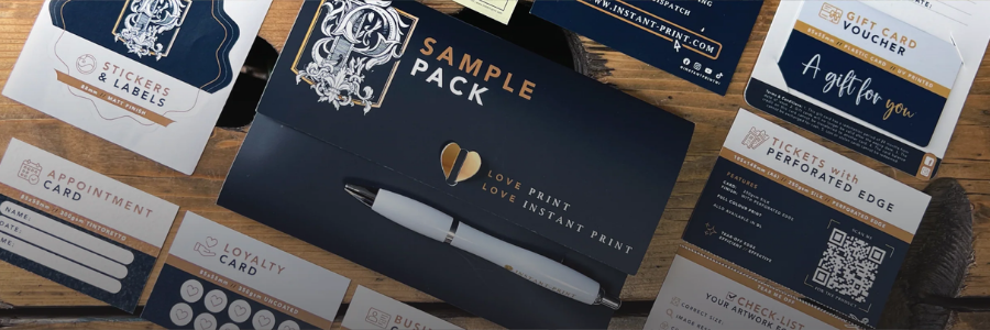 Collection of stationery items including a 'Sample Pack', a pen, and various cards on a wooden surface.